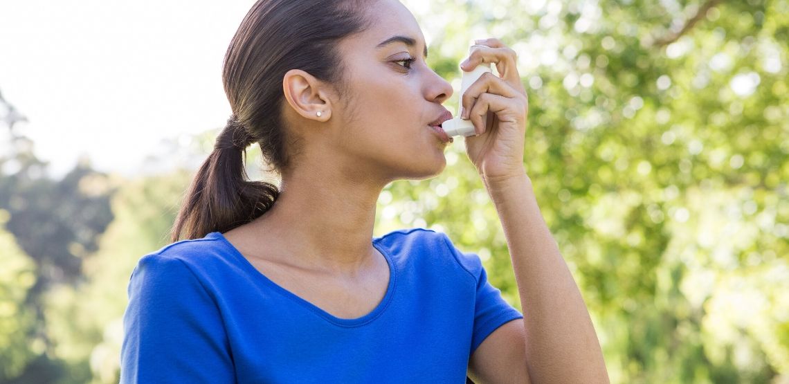 Someone using an inhaler.