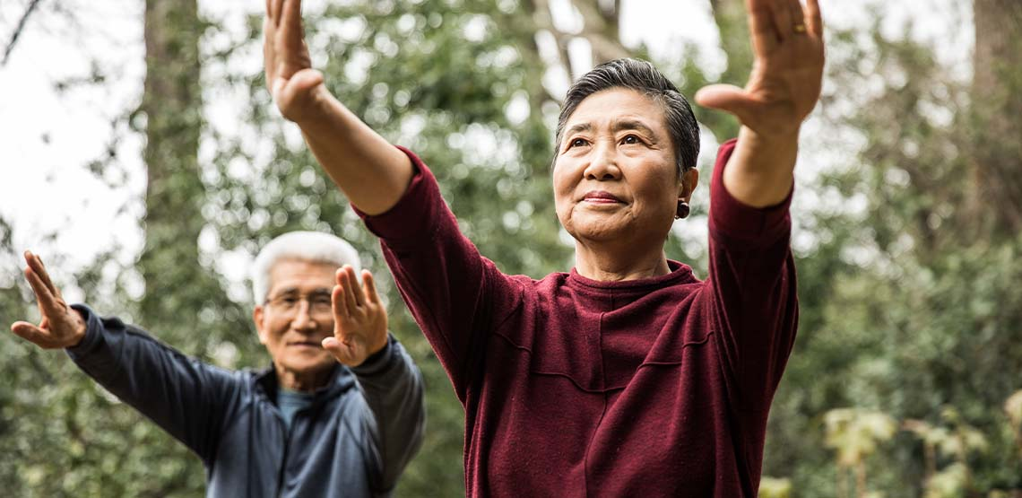 An elderly couple exercising outside.