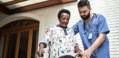 A nurse helping an older woman walk