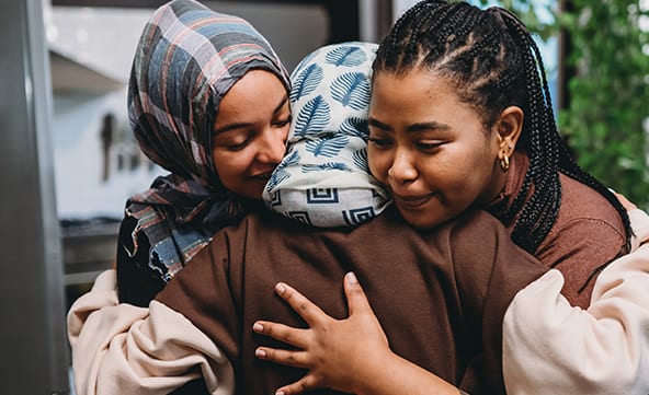 Three friends share a group hug