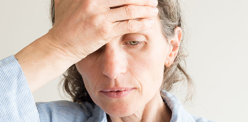 A woman is holding her hand to her head