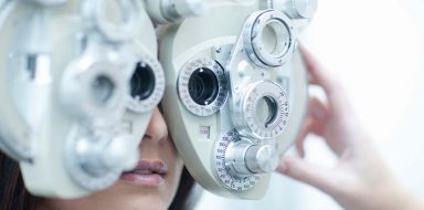 A person looking into an eye examination tool at the eye doctors.