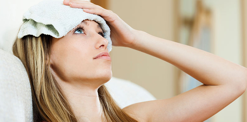 Woman is holding a wet cloth on her forehead