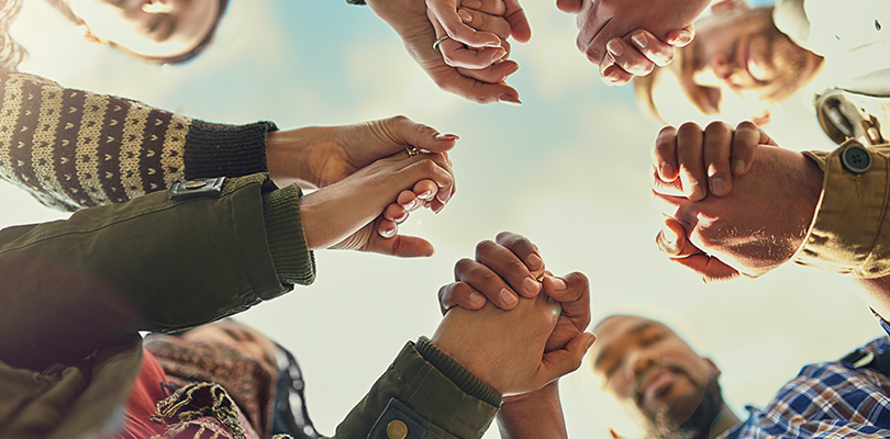 Small group of adults hold hands in a circle