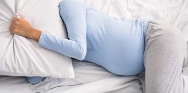 A pregnant woman laying in bed.