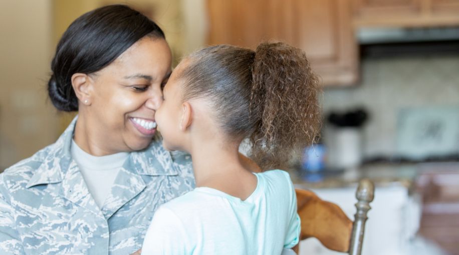 An older veteran woman and her child, facing each other and smiling.